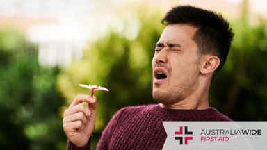 Man sneezing while holding a flower